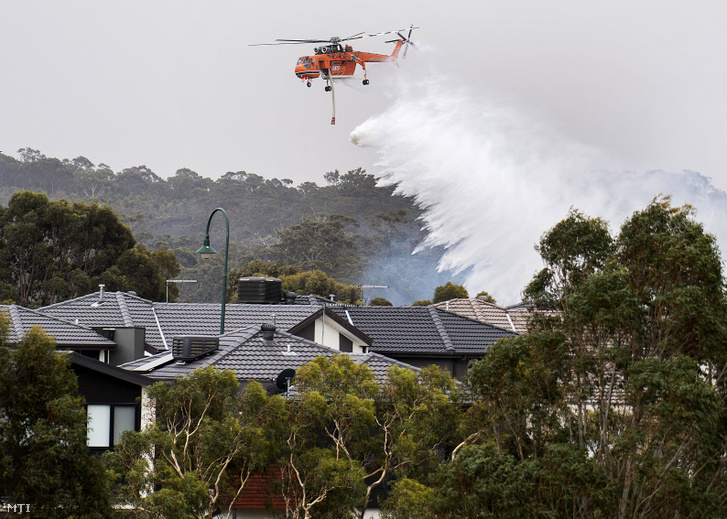 Helikopterről ledobott vízzel próbálják oltani a Victoria ausztrál szövetségi állambeli Bundoora közelében tomboló erdőtüzet 2019. december 30-án.