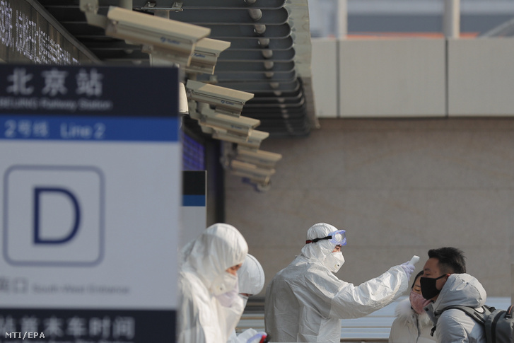 Védőruhába öltözött egészségügyi alkalmazottak egy utas hőmérsékletét vizsgálják egy pekingi metróállomáson 2020. január 25-én