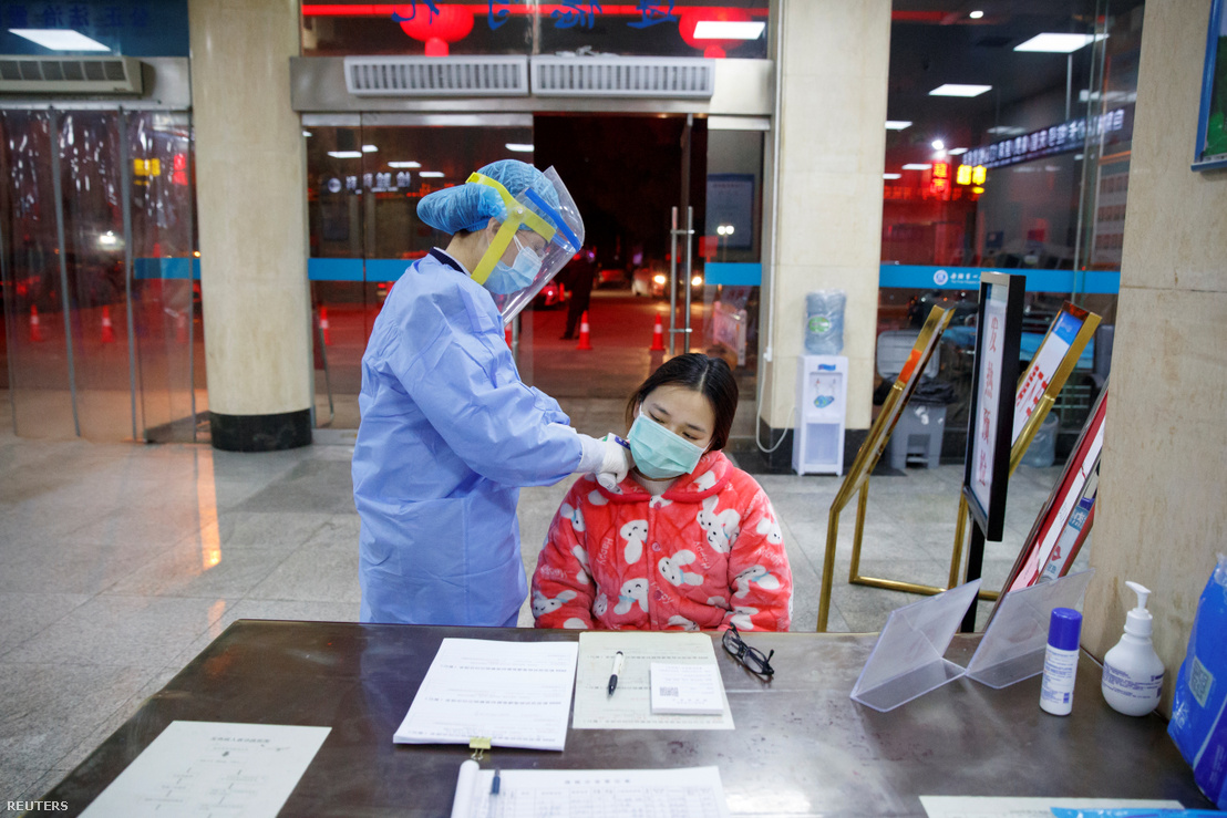 Nővér ellenőrzi a kórház recepcióján egy páciens testhőmérsékletét a yueyangi kórházban 2020. január 28-án