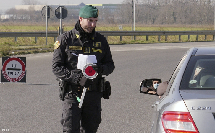 Rendőr ellenőriz egy sofőrt az észak-olaszországi Casalpusterlengónál felállított úttorlasznál 2020. február 24-én.