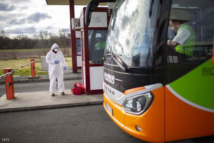 Egy érkező busz utasait ellenőrizik a koronavírus-járvány miatt