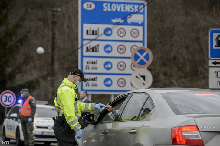Szlovák rendőr egy autós iratait ellenőrzi a Somoskőújfalui és Sátorosbánya közötti határátkelőhelyen 2020. március 13-án.