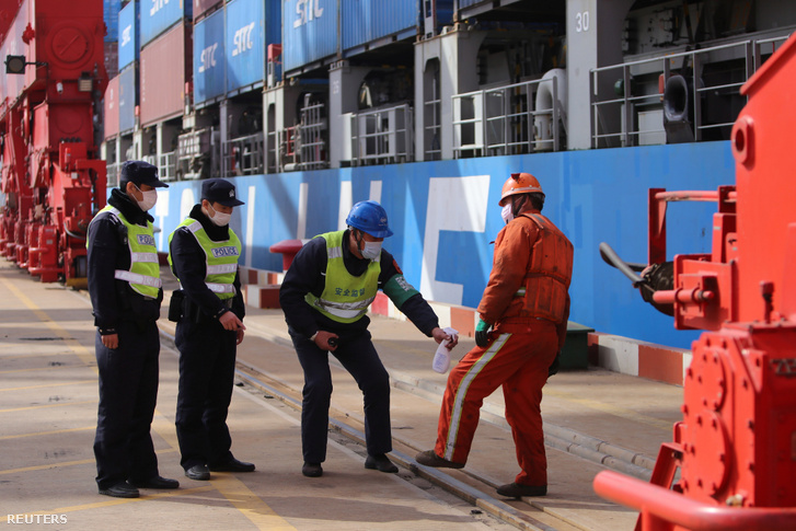 Dolgozót fertőtlenítenek a koronavírus miatt, a lianyungangi hajó konténer kikötőben 2020. március 13-án