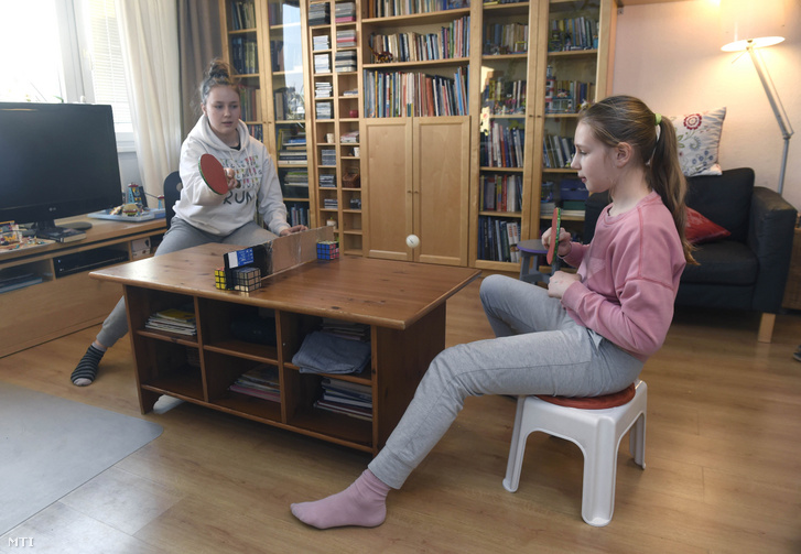 Általános iskolás lányok a tanulás közbeni szünetükben pingpongoznak budapesti otthonukban 2020. március 19-én