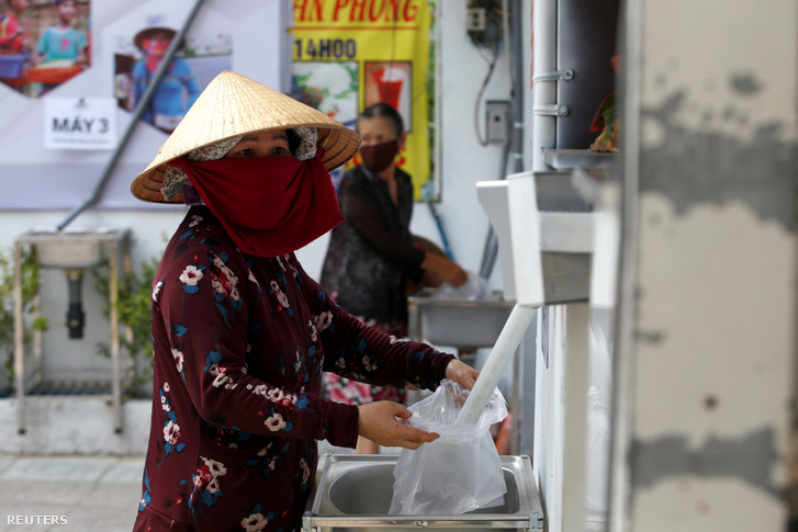 Egy nő tölti meg az üres zacskóját ingyenes rizzsel Ho Si Minh városában 2020. április 11-én