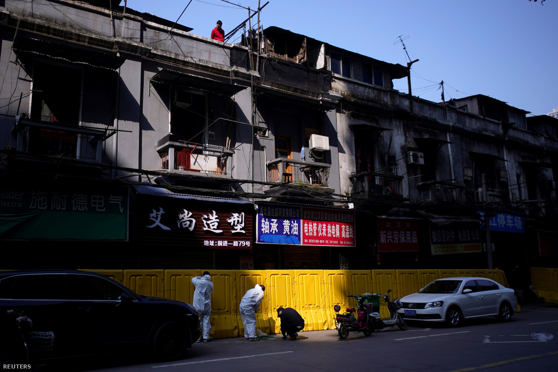 Védőöltözetet viselő munkások bontják el a koronavírus-járvány miatt felállított műanyag falakat, amivel a lakókat szeparálták el egymástól a kínai Vuhanban 2020. április 12-én. Hupej tartomány fővárosa volt a járvány kirobbanásának első gócpontja.