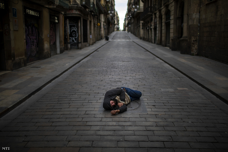 Hajléktalan férfi fekszik egy út közepén Barcelonában 2020. április 17-én