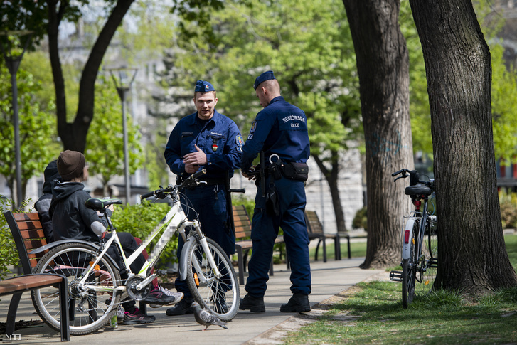 Járőröző rendőrök igazoltatnak fiatalokat a kijárási korlátozás idején Budapesten, az Erzsébet téren 2020. április 14-én