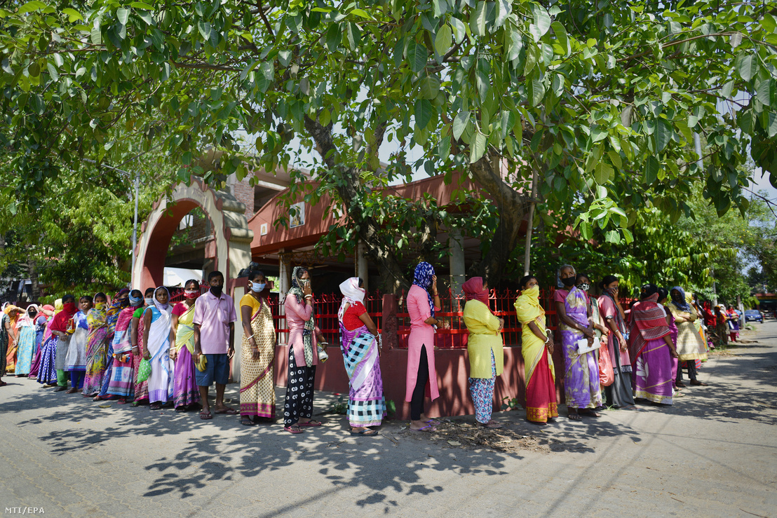 Szájmaszkot viselő asszonyok élelmiszercsomagért állnak sorban az indiai Asszám államban fekvő Gauhátiban