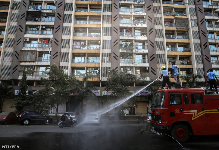 Fertőtlenítőszert fecskendeznek szét a tűzoltók a lakóépületek mellett az indiai Mira Bajandar városban