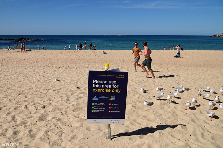 Kocogók a sydney-i Coogee tengerparti strandon 2020. április 22-én. Új-Dél-Wales ausztrál szövetségi államban a koronavírus-járvány terjedésének megfékezésére bevezetett szabályok megengedik az egyéni szabadidős sporttevékenységek gyakorlását a strandok többségén.