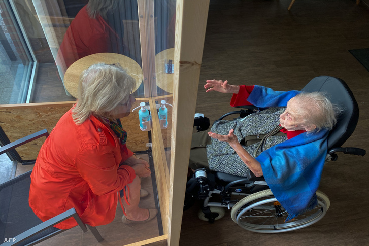 Látogató egy plexifalon keresztül beszélget a Les Jardins d'Astid idősotthon egyik lakójával 2020. április 29-én Maurage La Louviere-ben, Belgiumban