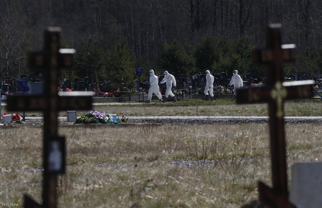 Védőruhát viselő temetői alkalmazottak egy koronavírus-járványban elhunyt ember temetését készítik elő Szentpétervár egyik temetőjének a járvány áldozatai számára elkülönített részében 2020. május 6-án.