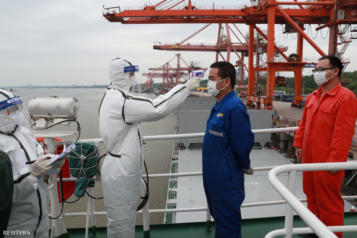 Kikötői dolgozó hőmérsékletét mérik egy vuhani teherhajó kikötőben 2020. május 9-én
