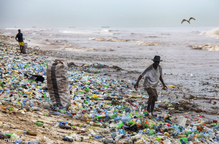 Ghánai férfiak újrahasznosítható anyagokat gyűjtenek a műanyag palackokkal borított Korle Gono tengerparti strandon Accrában 2016. június 12-én.