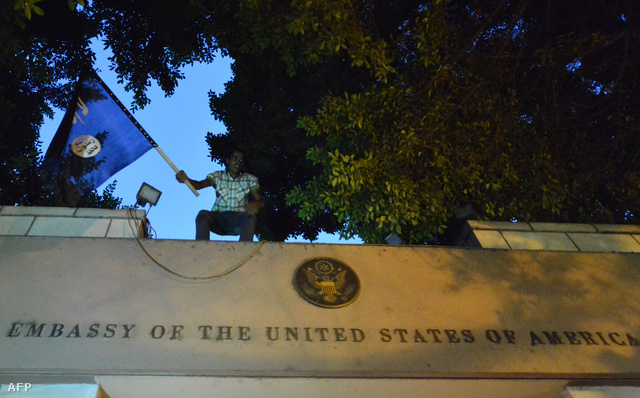 Tüntető az Egyesült Államok kairói nagykövetségének kapujának tetején. A zászlón a felirat: "Egy az Isten és Mohammed az ő prófétája"