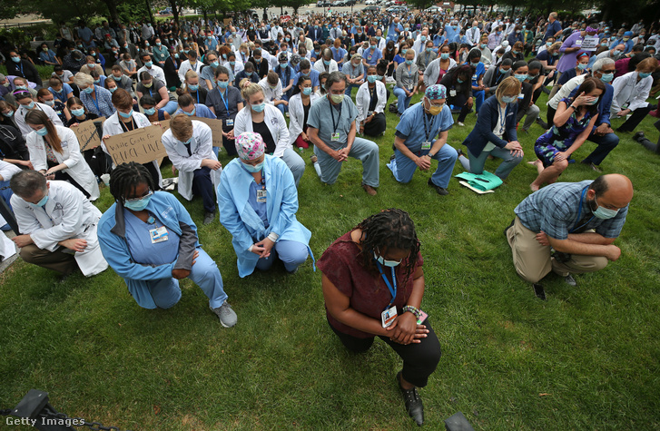 Egészségügyi dolgozók tiltakoznak a rasszizmus ellen, féltérdre ereszkedve Bostonban.
