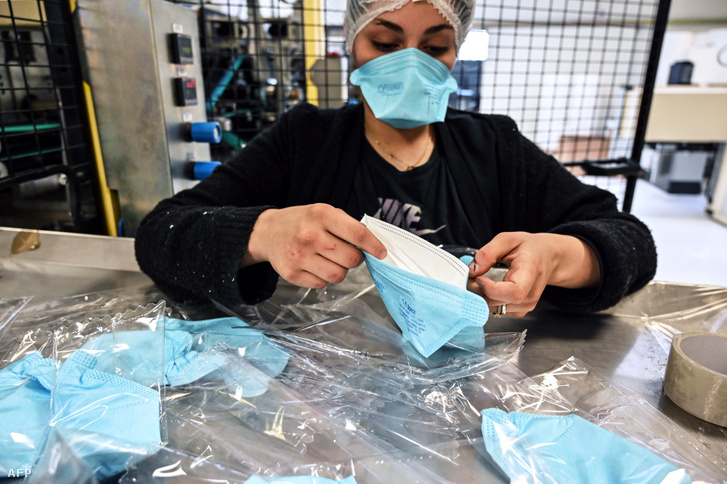 A Valmy védőmaszkokat gyártó cég üzemében futószalagon érkező munkavédelmi maszkokat csomagol egy alkalmazott a franciaországi Mablyban 2020. február 28-án