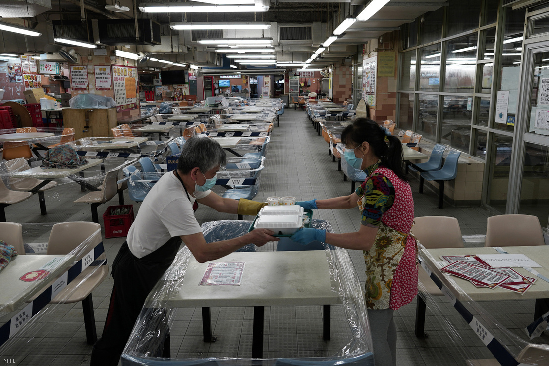 Védőmaszkos alkalmazottak elvitelre készítenek elő rendeléseket egy üres hongkongi kínai étteremben 2020. július 29-én, miután a koronavírus-járvány súlyosbodása miatt a hatóságok megtiltották a vendégfogadást az éttermekben, valamint kötelezővé tették a védőmaszk viselését minden nyilvános helyen.