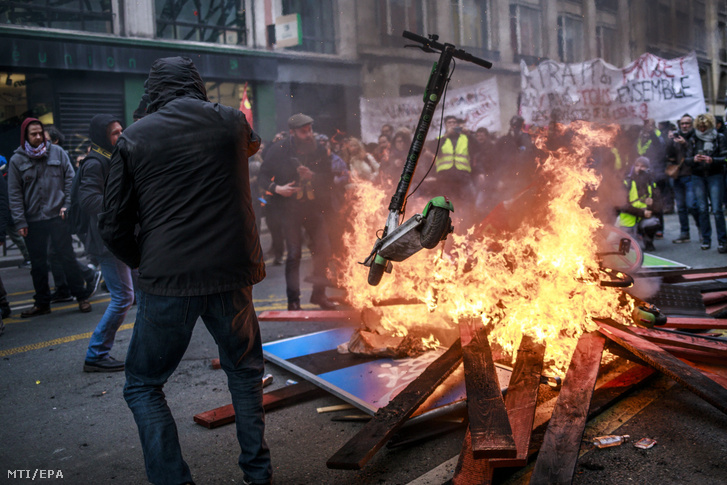 Az egyik tüntető scootert hajít a tűzbe egy felgyújtott útakadálynál Párizsban a kormány tervezett nyugdíjreformját ellenző általános sztrájk huszonnegyedik napján, 2019. december 28-án. A szakszervezetek december 4-én határozatlan idejű munkabeszüntetést hirdettek a jelenlegi 42-féle nyugdíjrendszer egységesítésére irányuló, pontrendszer alapú reformtervezet ellen.