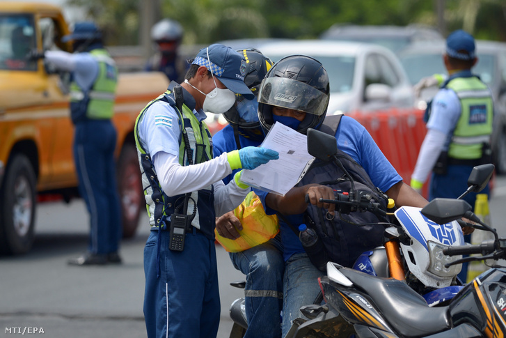 Rendőr ellenőrzi az ecuadori Guayaquil városba érkezők okmányait egy ellenőrző ponton 2020. április 23-án, a koronavírus-járvány idején