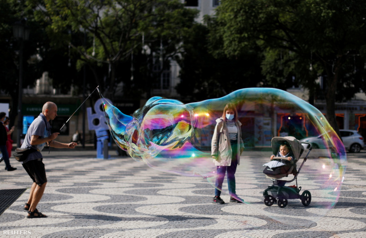 Utcai művész szappanbuborékot fúj Lisszabonban 2020. október 31-én