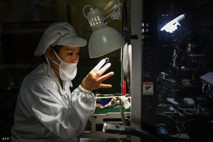 Optikai üveget ellenőriz egy munkás a Wanxin Optikai gyárban Zhenjiangban 2020. október 12-én