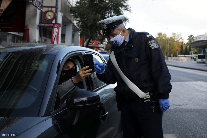 Rendőr ellenőrzi egy autós iratait a koronavírus-járvány miatt elrendelt lezárás ideje alatt Athénban 2020. november 7-én