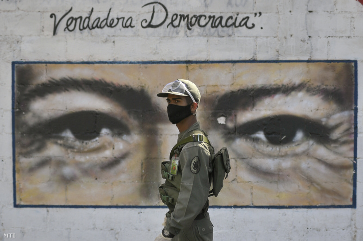 Katona járõrözik egy caracasi szavazóhelyiség elõtt a venezuelai parlamenti választások napján 2020. december 6-án. A szavzóhelyiségként mûködõ iskola falán Hugo Chavez korábbi venezuelai elnök arcát ábrázoló képet festettek.