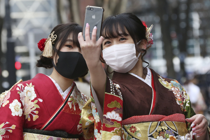 Kimonót és a koronavírus-járvány miatt védőmaszkot viselő nők fényképezkednek a nagykorúsági nap alkalmából rendezett ünnepségről távozóban a Tokió melletti Jokohamában 2021. január 11-én. Japánban a fiatalok a huszadik életévük betöltésekor válnak nagykorúvá.