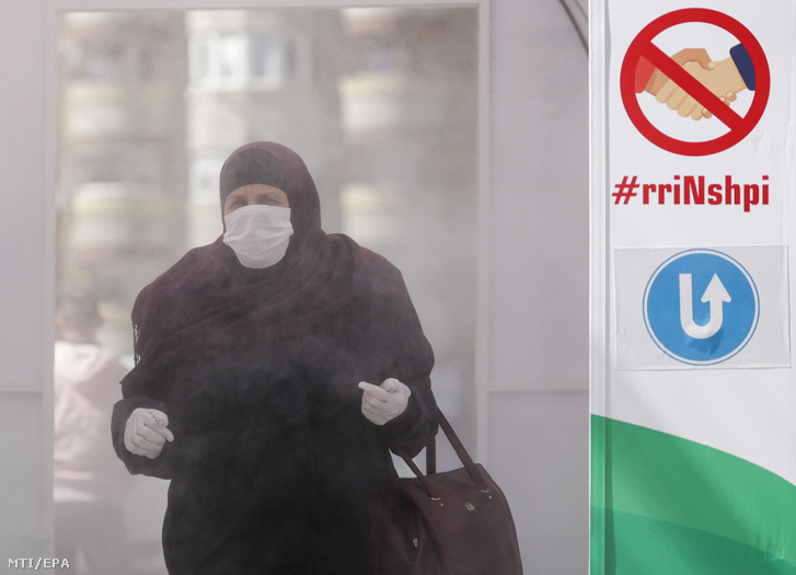 A koronavírus-járvány elleni védekezésképpen felállított fertőtlenítő-alagúton megy keresztül egy nő Mitrovicában