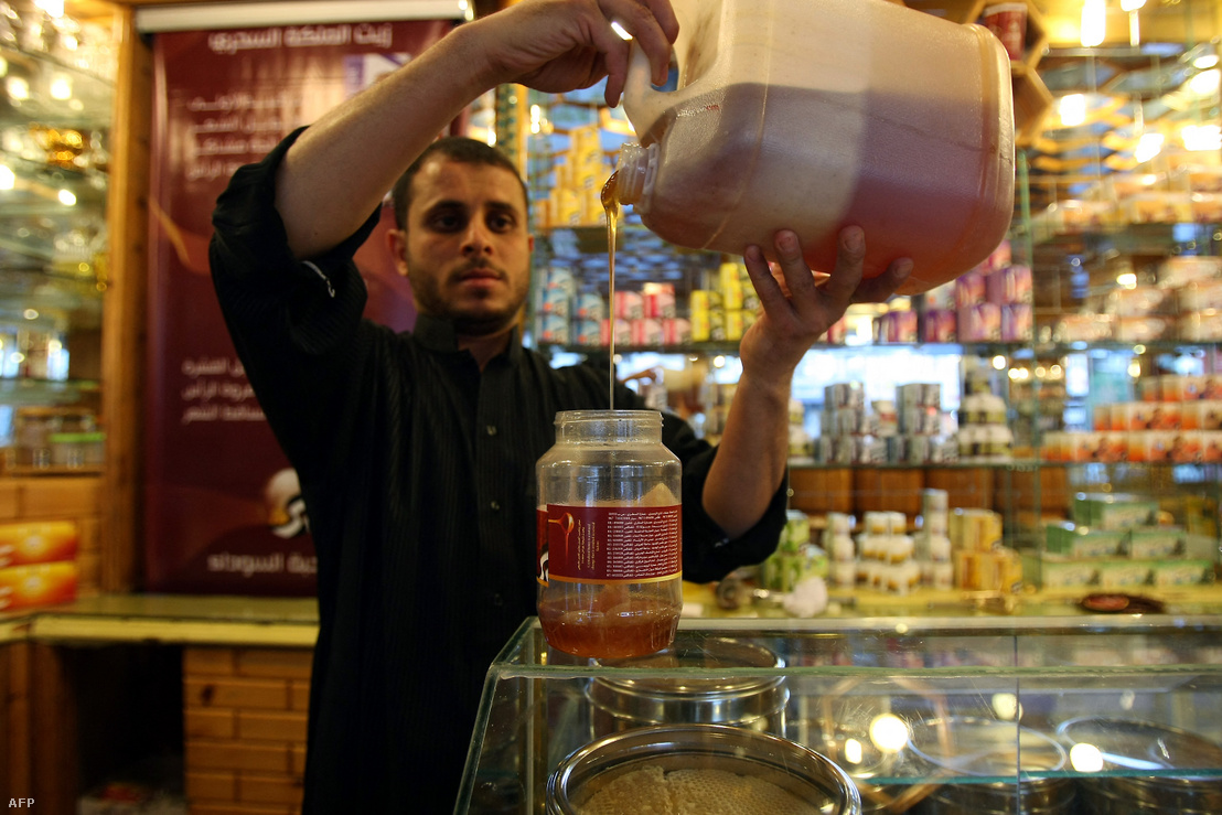 Egy jemeni árus mézet önt egy üvegbe üzletében, 2012-ben