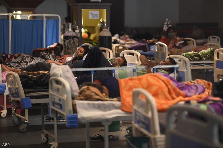 A betegek oxigénmaszkok segítségével lélegeznek egy bankett-teremben, amelyet 2021. április 27-én ideiglenesen Covid-19 koronavírus kórházzá alakítottak át Új-Delhiben