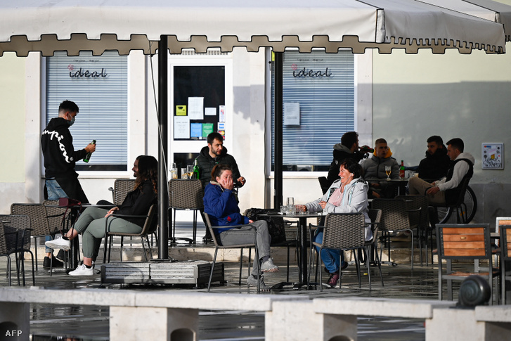 Emberek ülnek egy kávézó teraszán 2021. április 19-én Piran városában, Szlovéniában