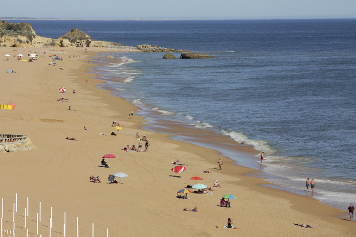 Strandoló emberek a Portugália déli részén fekvő Albufeira Falesia nevű tengerparti strandján 2021. május 17-én. Ezen a napon megérkeztek az első brit turistacsoportok Portugáliába, miután mindkét ország enyhítette a koronavírus-járvány miatt elrendelt korlátozásokat