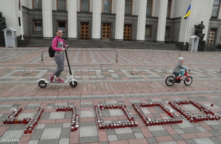 A koronavírus 47 ezer ukrán áldozatának emlékére elhelyezett mécsesek előtt megy egy nő gyermekével a kijevi parlamentnél 2021. május 17-én. Ukrajnában több mint 47 ezren vesztették életüket a koronavírus következtében