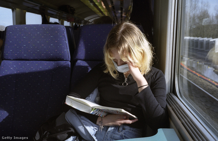 Egy nő maszkot visel, miközben könyvet olvas egy vonaton Brugge és Gent között 2021. február 20-án