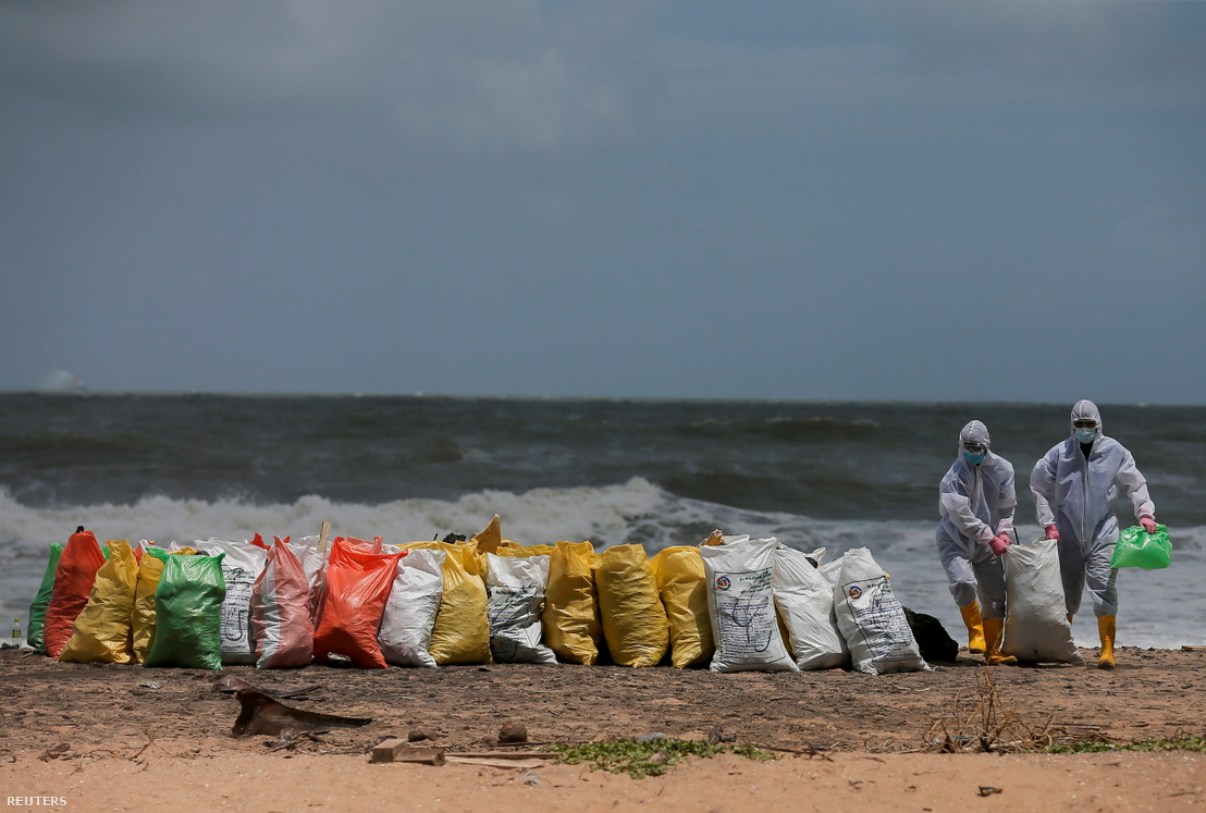 A Srí Lanka-i haditengerészet tagjai eltávolítják a strandra mosott törmeléket az MV X-Press Pearl konténerszállító hajóról 2021. május 27-én