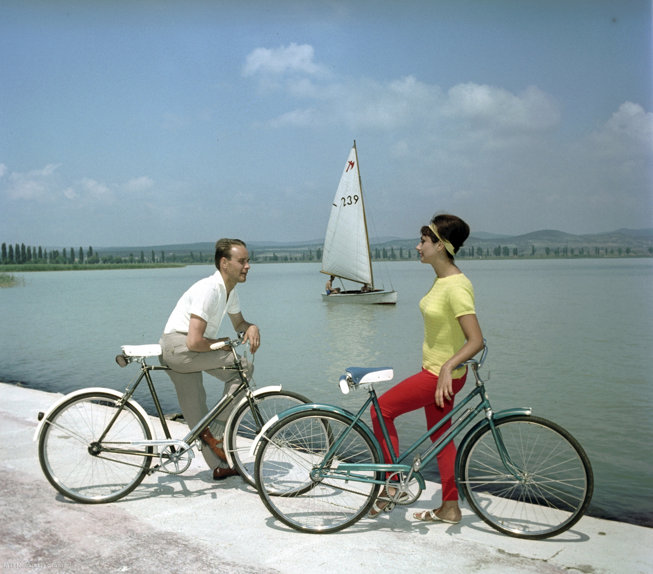 Tihany, 1963. június 8. A Csepel Vas- és Fémművek Kerékpárgyárában készült női és férfi kerékpárokat reklámozza Saáry Éva modell és társa a Balaton partján a Tihanyi-félsziget Gödrös-strandján a PANNONIA Külkereskedelmi Vállalat számára készült fotón. A háttérben Balatonfüred