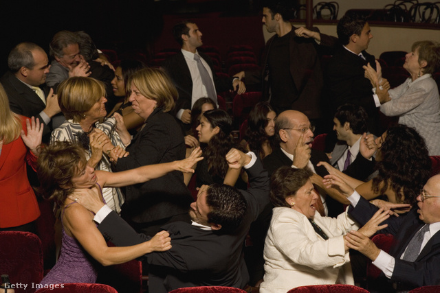 A színházi nézőtéren megtanítják egymást kesztyűbe dudálni: az ok ismeretlen.