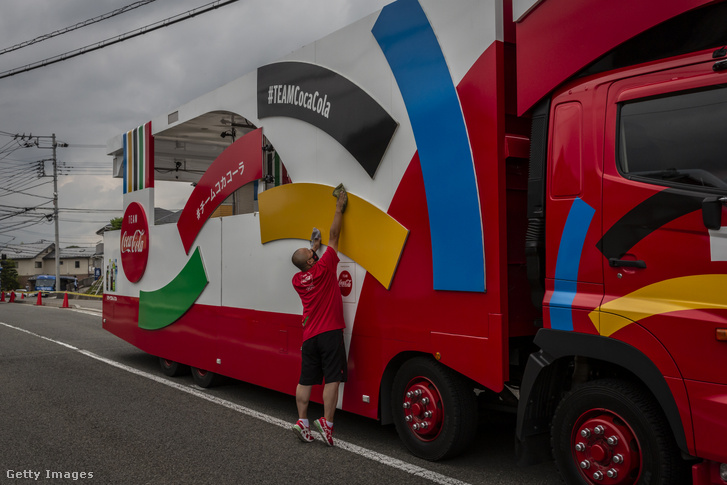 A személyzet egyik tagja tisztít egy szponzor járművet a tokiói olimpiai játékok fáklyafutása előtt 2021. június 26-án, Hokutoban, Japánban