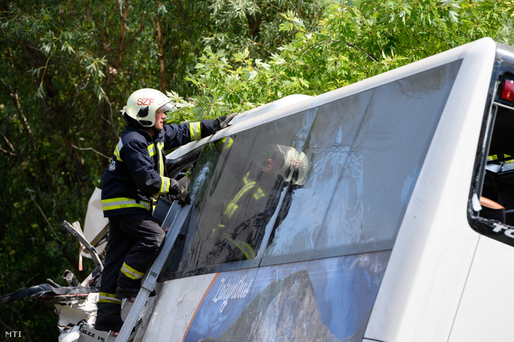 Tűzoltók kiemelik az árokból a hajnalban balesetet szenvedett autóbuszt az M7-es autópálya mellett Szabadbattyán közelében 2021. augusztus 15-én