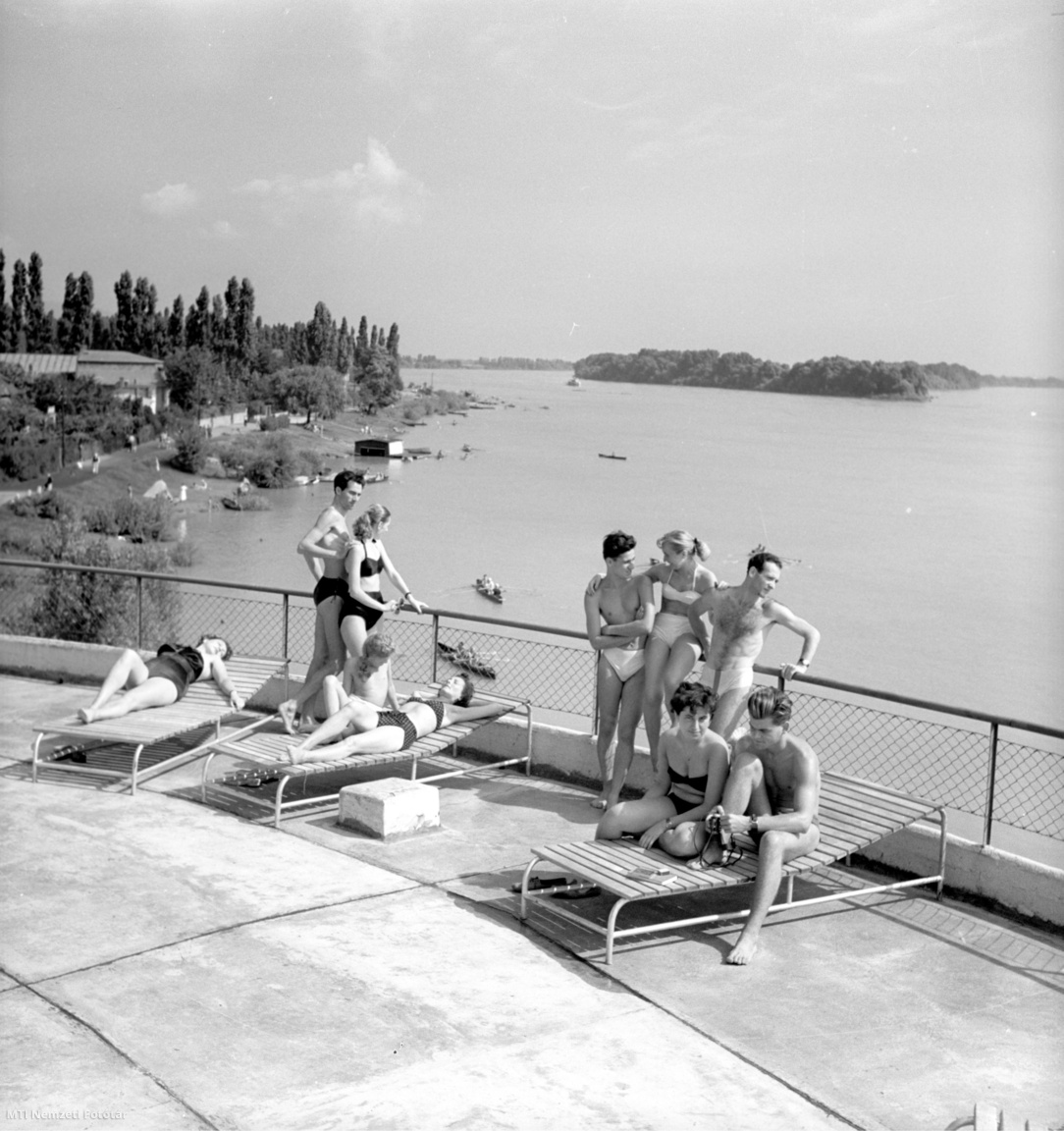 1955. augusztus 9.  Fiatalok fürdőruhában napoznak egy épület tetőteraszán a Római-parton, háttérben a Duna