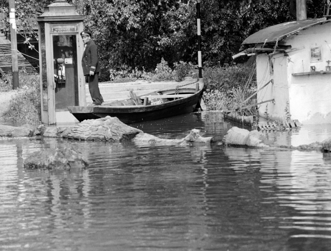 Egy matróz csónakban áll a megáradt Duna folyó mellett egy népszigeti telefonfülkénél 1965. június 17-én. Az árvízi mentésben több a feladatuk a vízi rendészeti szerveknek. A kiürített házak a könnyű zsákmány reményében vonzzák a bűnözőket, ezért a Budapesti Vízirendőrőrs teljes létszáma készenlétben van, hajókkal éjjel-nappal járják az elöntött területeket, hogy megakadályozzák a bűncselekményeket, fosztogatásokat. A járőrök irányítják az önkéntes rendőröket, figyelik a gátakat, segítenek a mentésben is az elsődleges feladatuk, a közbiztonság megőrzése mellett.