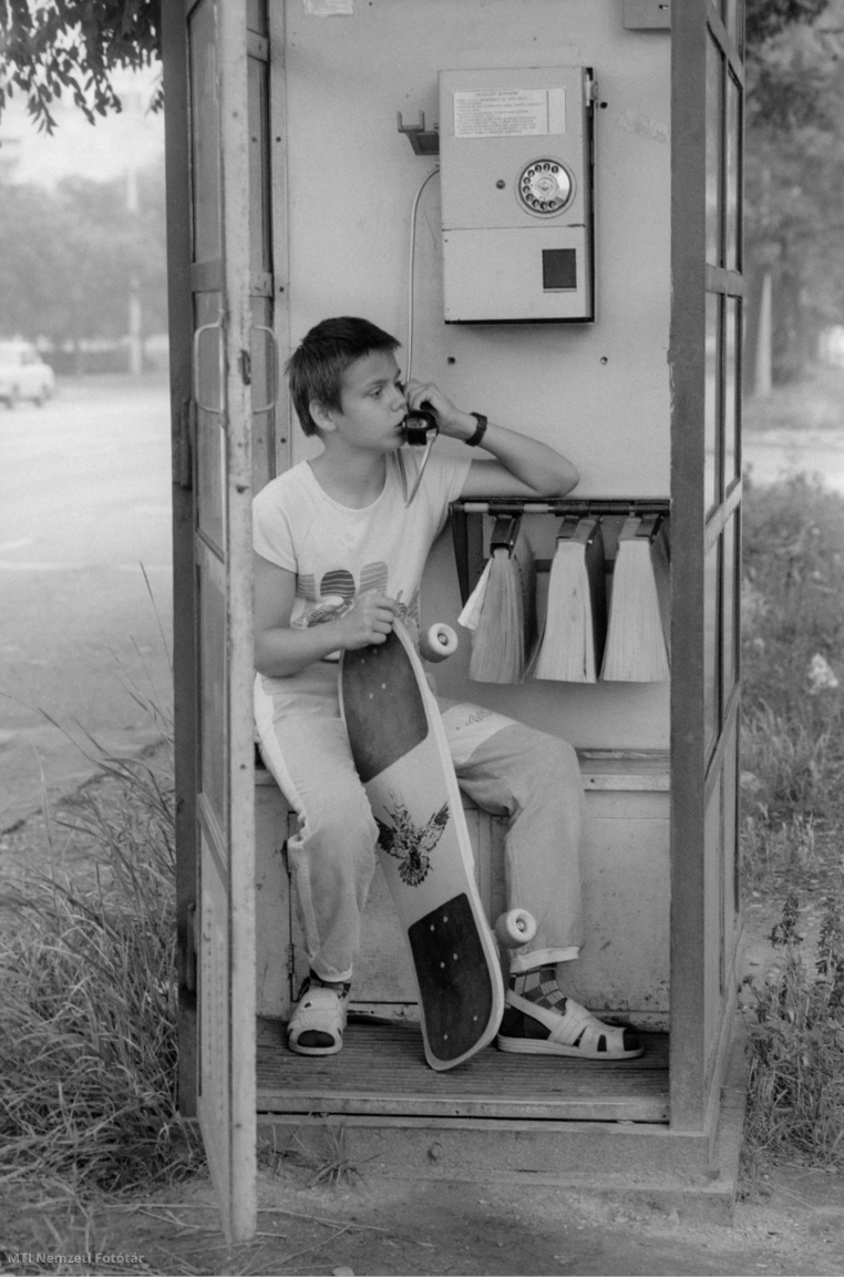 Gördeszkás fiú telefonál egy utcai fülkében 1989 júniusában