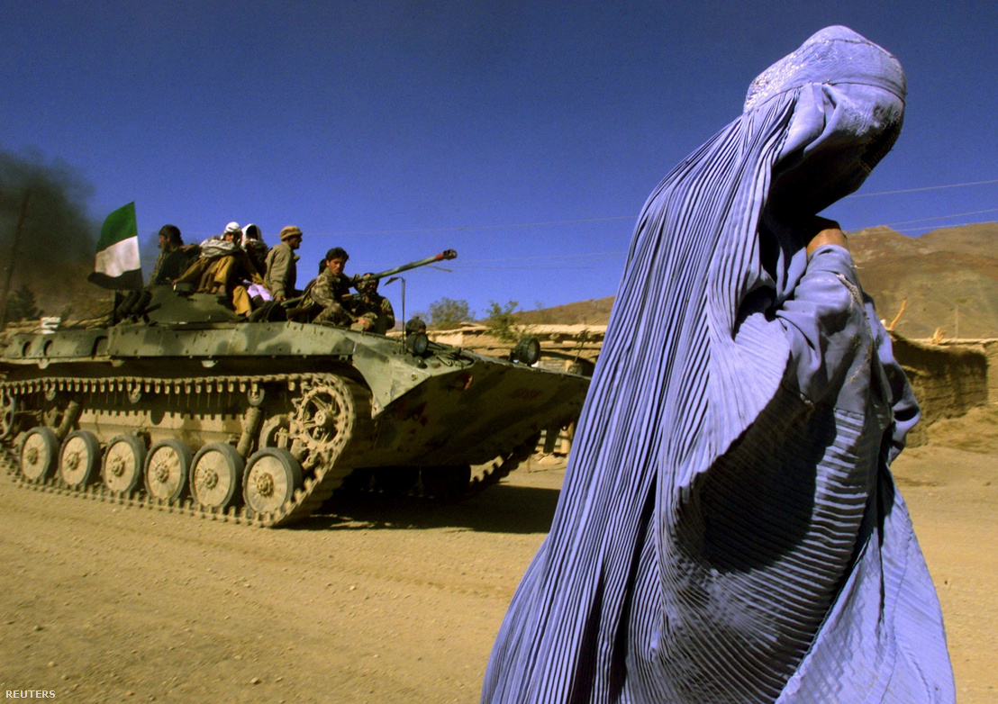 Burkát viselő afgán nő mellett halad el az Északi Szövetség harckocsija. A tálibok ellen harcoló katonai csoport 2001-ben, amerikai légi támogatással elfoglalta Kabult. Ezt követően egyik parancsnokuk, Hámid Karzai alapított meg az átmeneti kormányt. Jabal os Saraj tartomány, 2001. november 4.