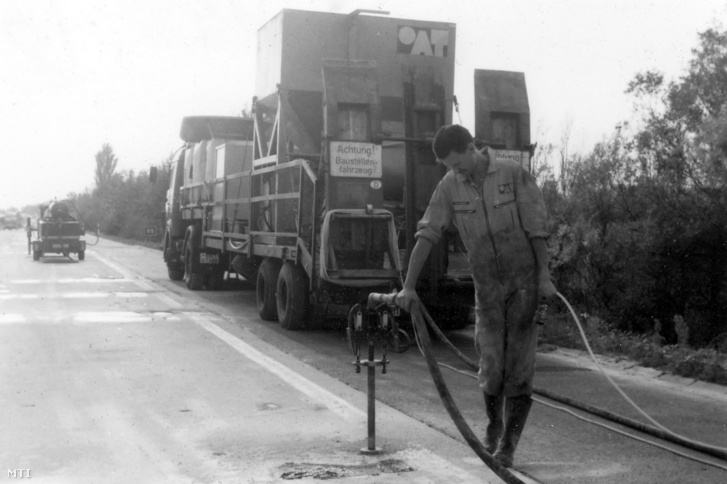 Egy munkás javítja az M7-es autópálya megsüllyedt beton úttestét 1993. október 14-én. Az eljárásnak az a lényege, hogy a megsüllyedt betontáblákat megemelik, szintbe helyezik, alátömítik, majd stabilizálják a talajt