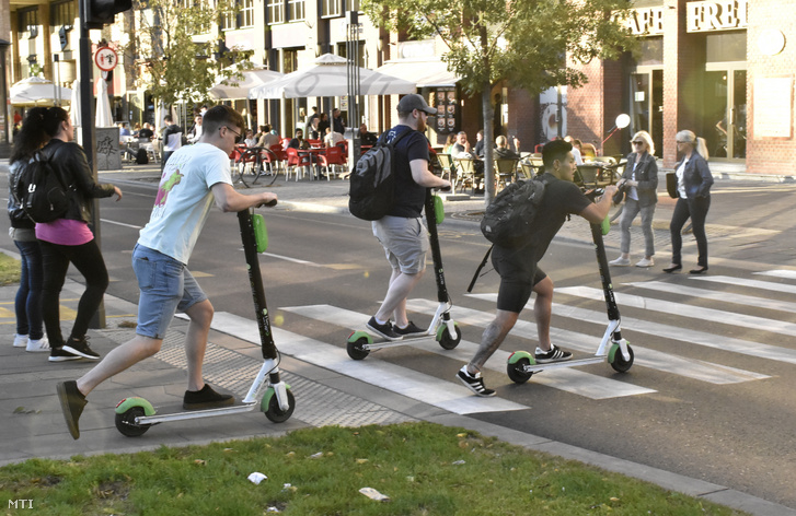 Elektromos rollerrel közlekedő fiatalok egy Károly körúti gyalogátkelőnél
