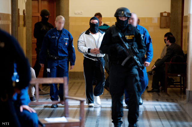 2012. július 15. Rendőrök és kommandósok vezetik elő L. Jánost a Pesti Központi Kerületi Bíróság (PKKB) folyosóján.