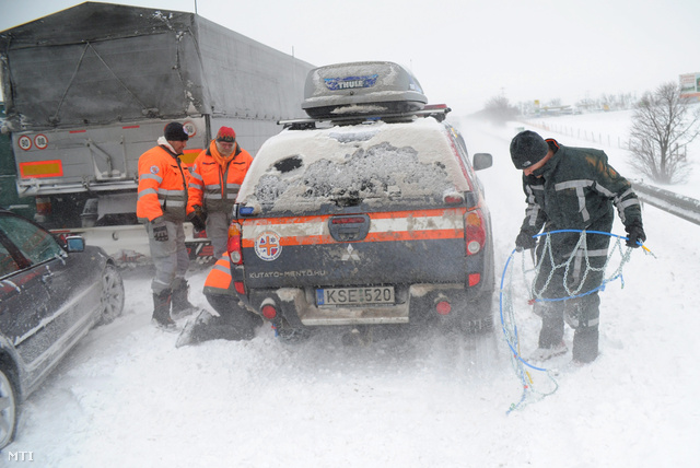 Hóláncot szerelnek a Pest Megyei Kutató-Mentő Szolgálat autójára az M7-es autópályán 2013. március 15-én. A mentőszolgálat dolgozói Fejér megyébe indultak hogy elakadt mentőket mentsenek ki a hó fogságából.